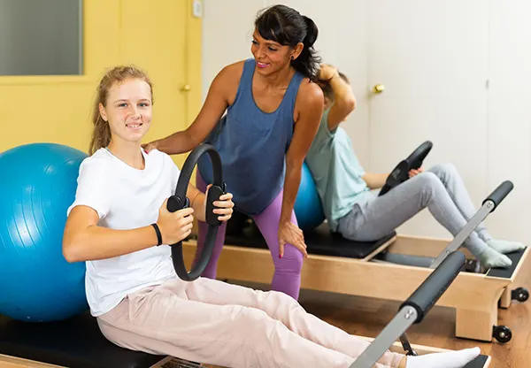 Fisioterapeuta acompanhando aluno no Pilates
